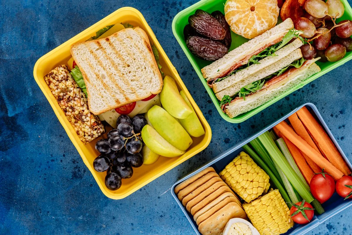 Colorful lunch boxes with sandwiches, fruit and vegetables.